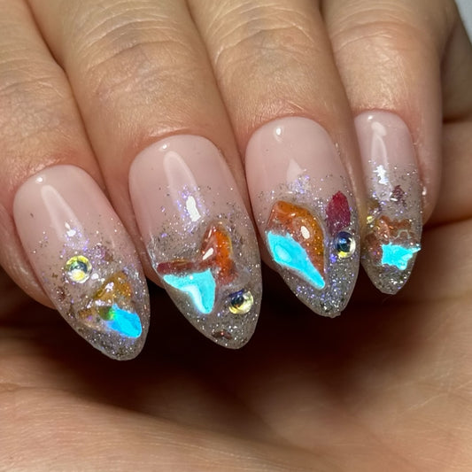  Photo de présentation des Press On Nails "Gems" : ongles avec un dégradé de paillettes et des incrustations de cristaux aux reflets bleu azur.