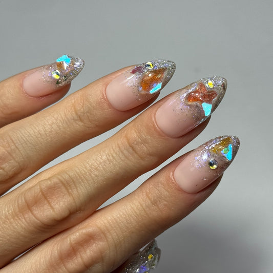  Photo de présentation des Press On Nails "Gems" : ongles avec un dégradé de paillettes et des incrustations de cristaux aux reflets bleu azur.