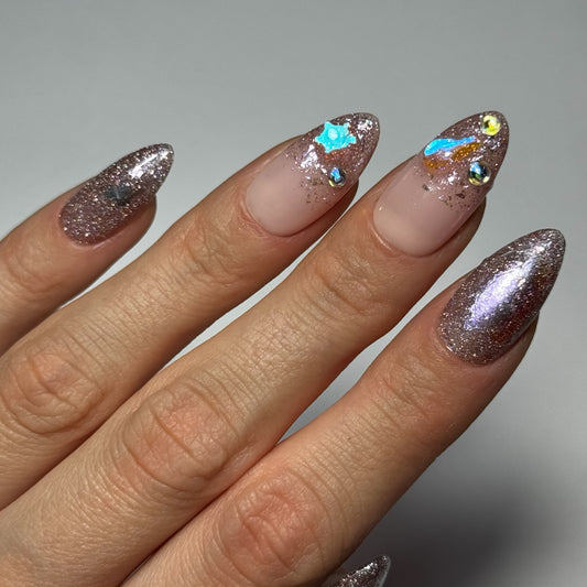 Photo du produit "Coachella" : des Press On Nails faits à la main en France, sur une base nude avec des paillettes et des strass de différents reflets de couleur, créant un effet festif et glamour.